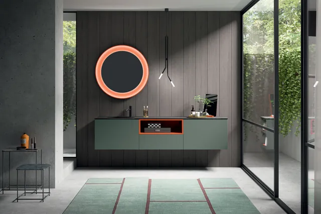 Mobile bagno CartaBianca verde sospeso con specchio circolare dalla cornice arancione.