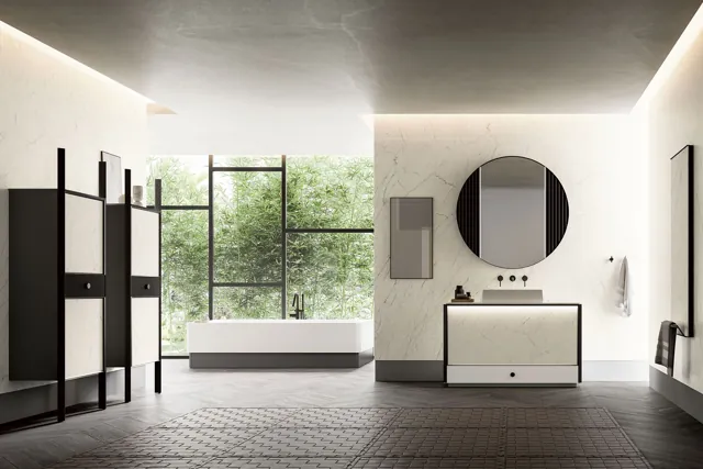 Ambiente bagno Honey luminoso con mobile chiaro, strutture scure e vasca vicino alle finestre.