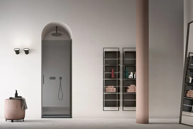 Sistema doccia Nude in una nicchia ad arco con vetri trasparenti e vasca vicina.
