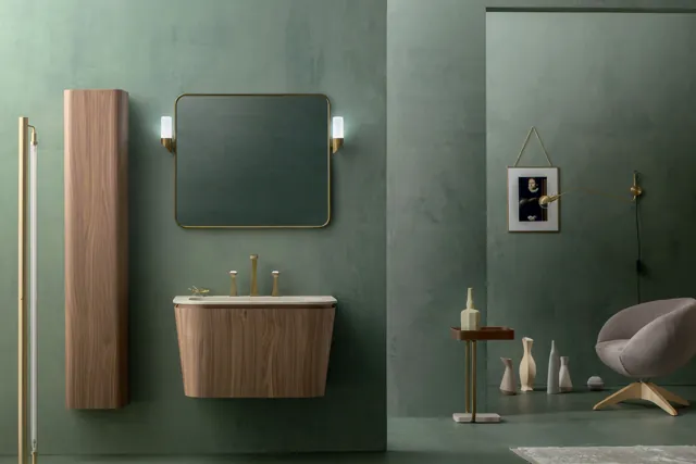 Mobile Suede sospeso dai profili curvi con specchio arrotondato in un bagno verde.