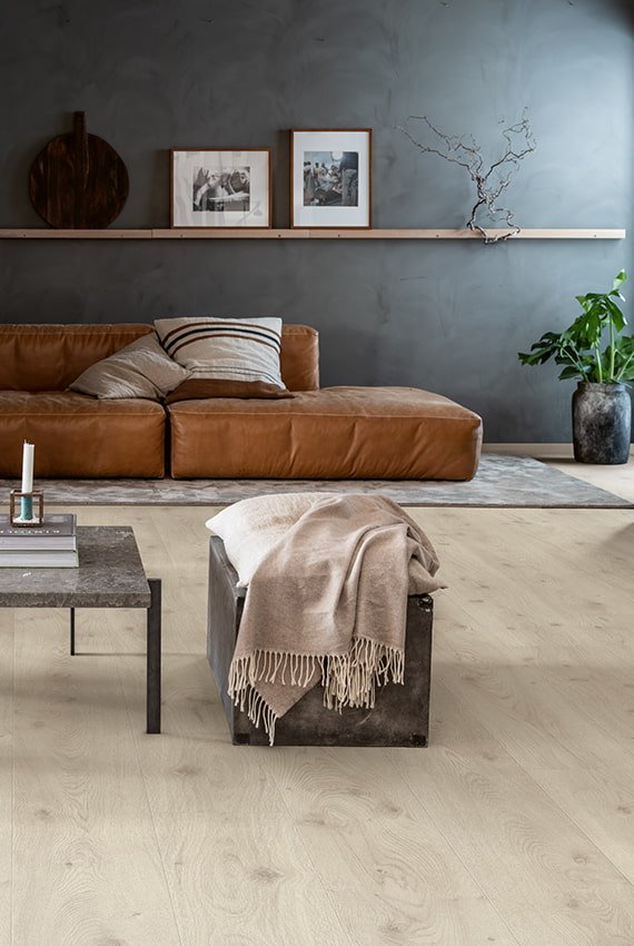 Ambientazione Pergo con pavimento in laminato effetto rovere e divano marrone